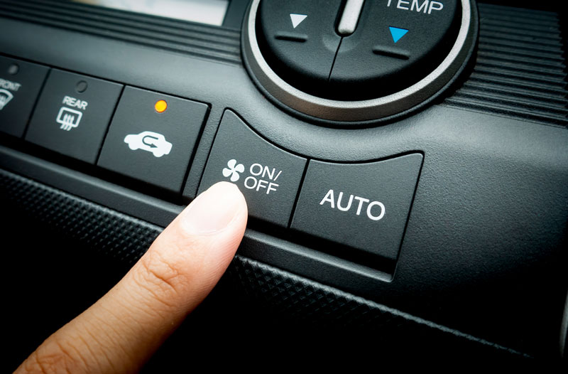 a finger pressing on Power switch of a Car air conditioning system
